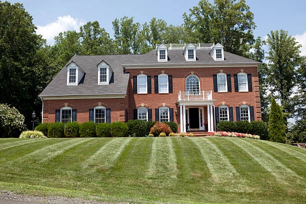 Red bricked house on grass with trees behind -colonial red brick remodel exterior