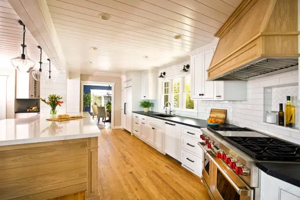 Bright kitchen with white cabinets, wood accents, and a large island featuring modern appliances. -kitchen remodel contractor