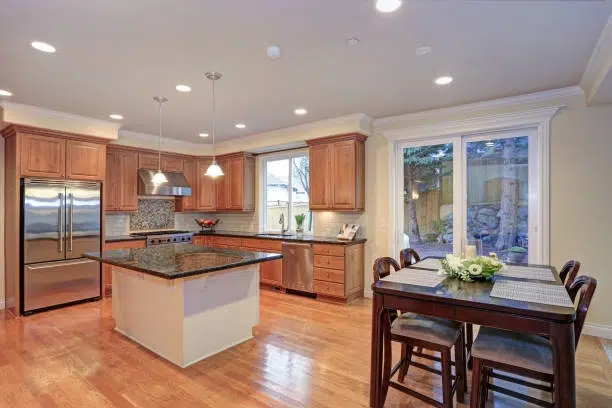 Warm kitchen with wooden cabinets, granite island, and bright dining space. -kitchen remodel for small kitchen