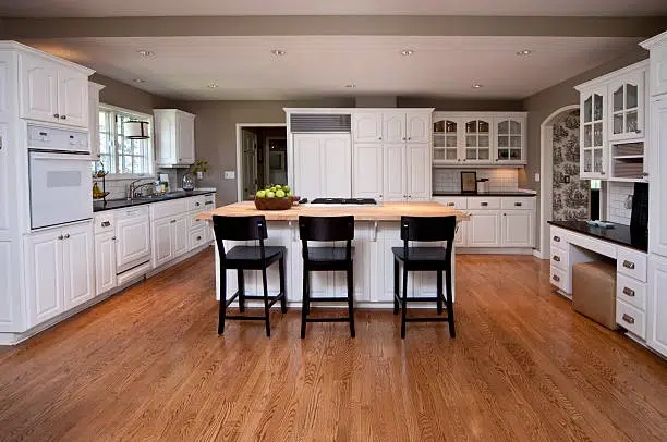 Spacious kitchen with white cabinets, wooden floors, and large island. -contractor remodel kitchen