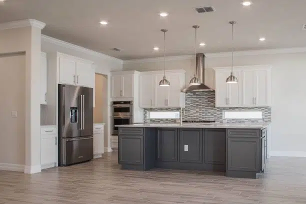 Modern kitchen with dark island, stainless appliances, pendant lights, and backsplash. -contractor remodel kitchen