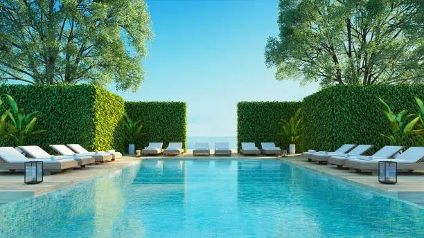 Luxurious outdoor pool with lounge chairs, greenery, and privacy hedges. -pool and decks