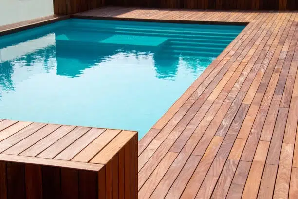 Minimalist pool with wooden deck, steps, and clean, modern design. -deck and pools