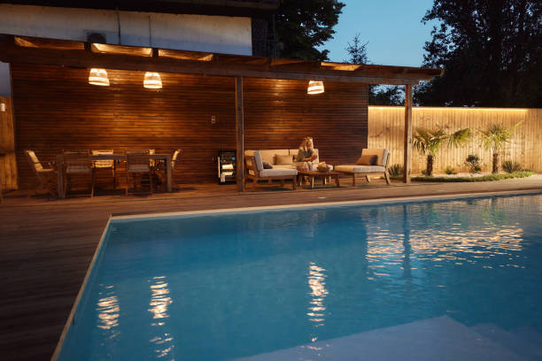 Evening poolside lounge with cozy seating, wooden deck, and lighting. -deck and pools