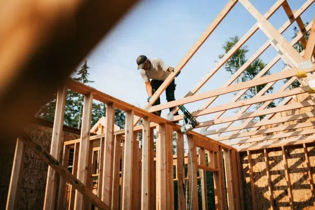 Worker installing wooden roof frame, part of new construction homes in California.