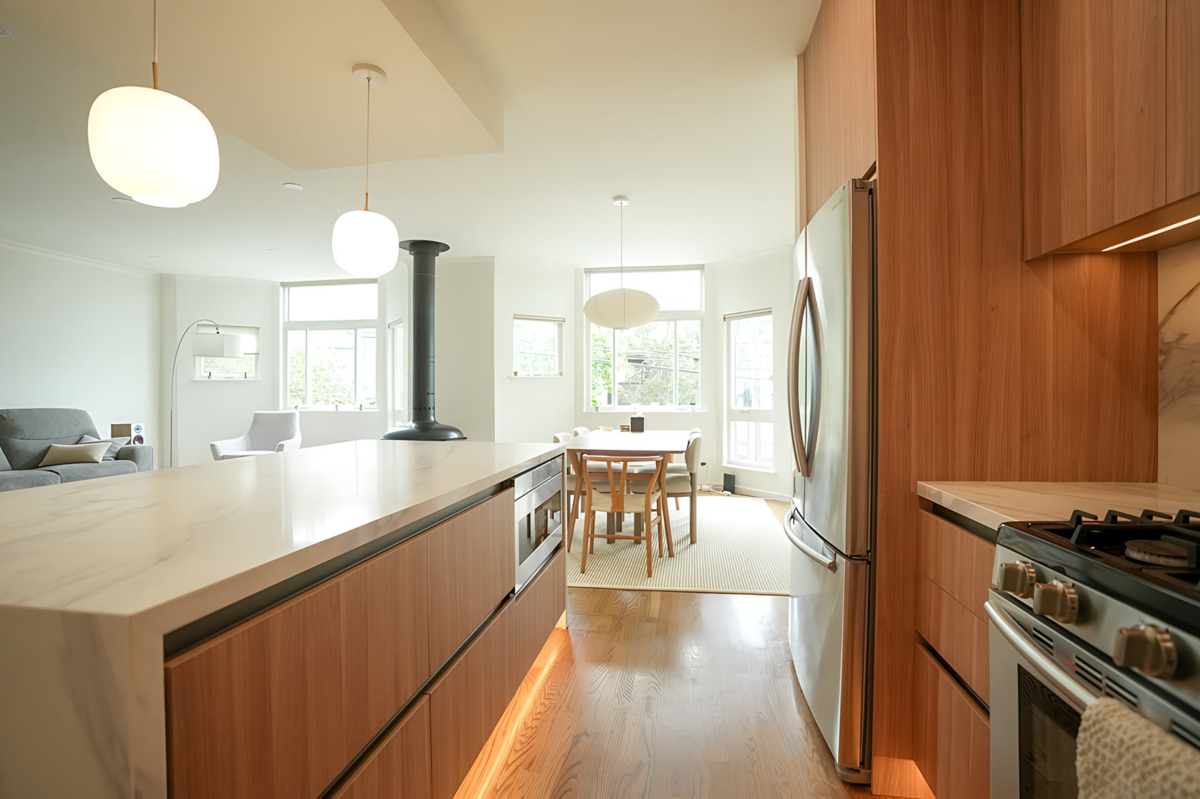 Open-plan kitchen remodel with wood cabinets, a breakfast peninsula and pendant lighting